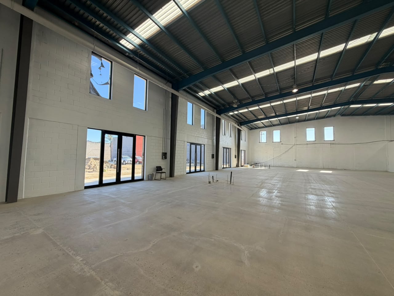 Interior de nave industrial de doble altura en Tijuana, con estructura metálica, cantil de cristal al frente y piso de concreto pulido