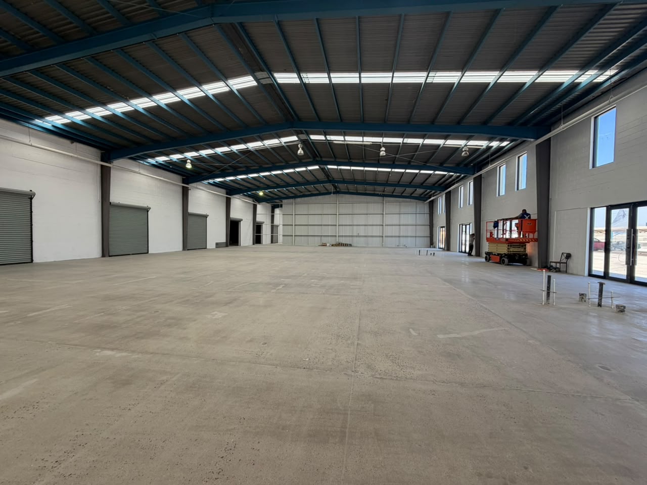 Nave industrial de doble altura con cortinas de carga a la izquierda y cantil de cristal al fondo, Tijuana