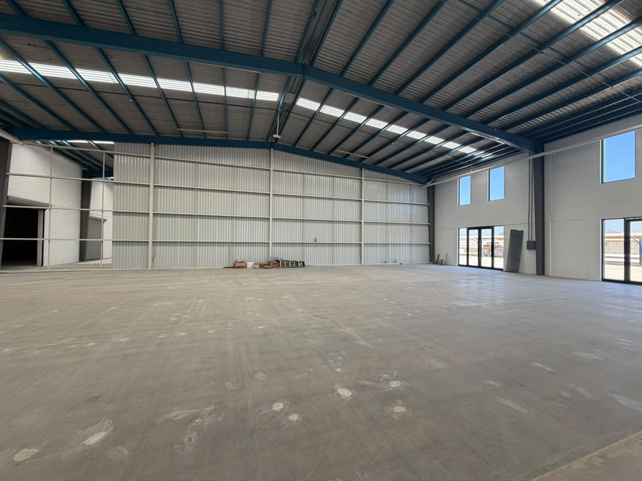 Bodega industrial vacía con muro de lámina, piso de concreto pulido y acceso de cristal, Tijuana
